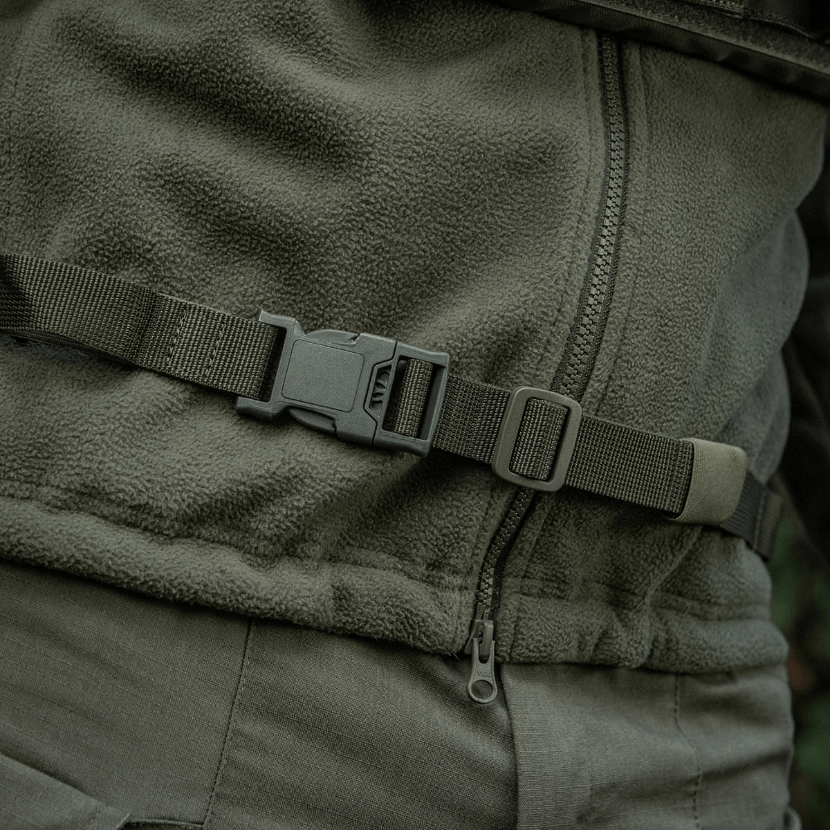 Grøn M-Tac Siddeunderlag med bælte vist omkring en jakke