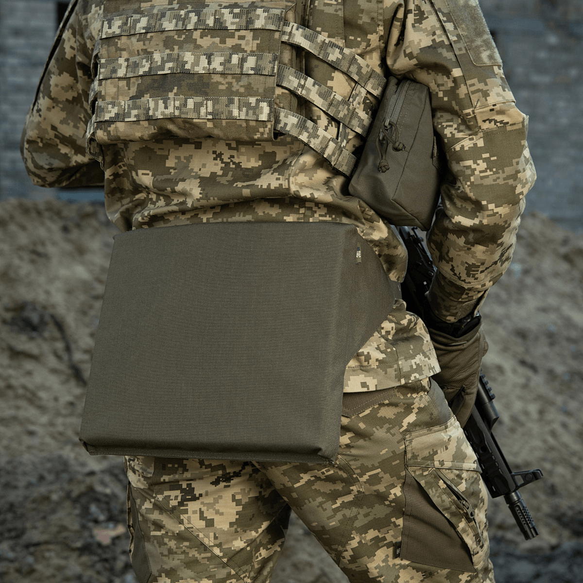 M-Tac Siddeunderlag med bælte på en kamuflage uniform, velegnet til udendørs brug og militært udstyr.