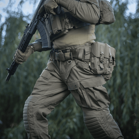 Person wearing M-Tac War Belt ARMOR and tactical gear in the field, ready for combat tasks.