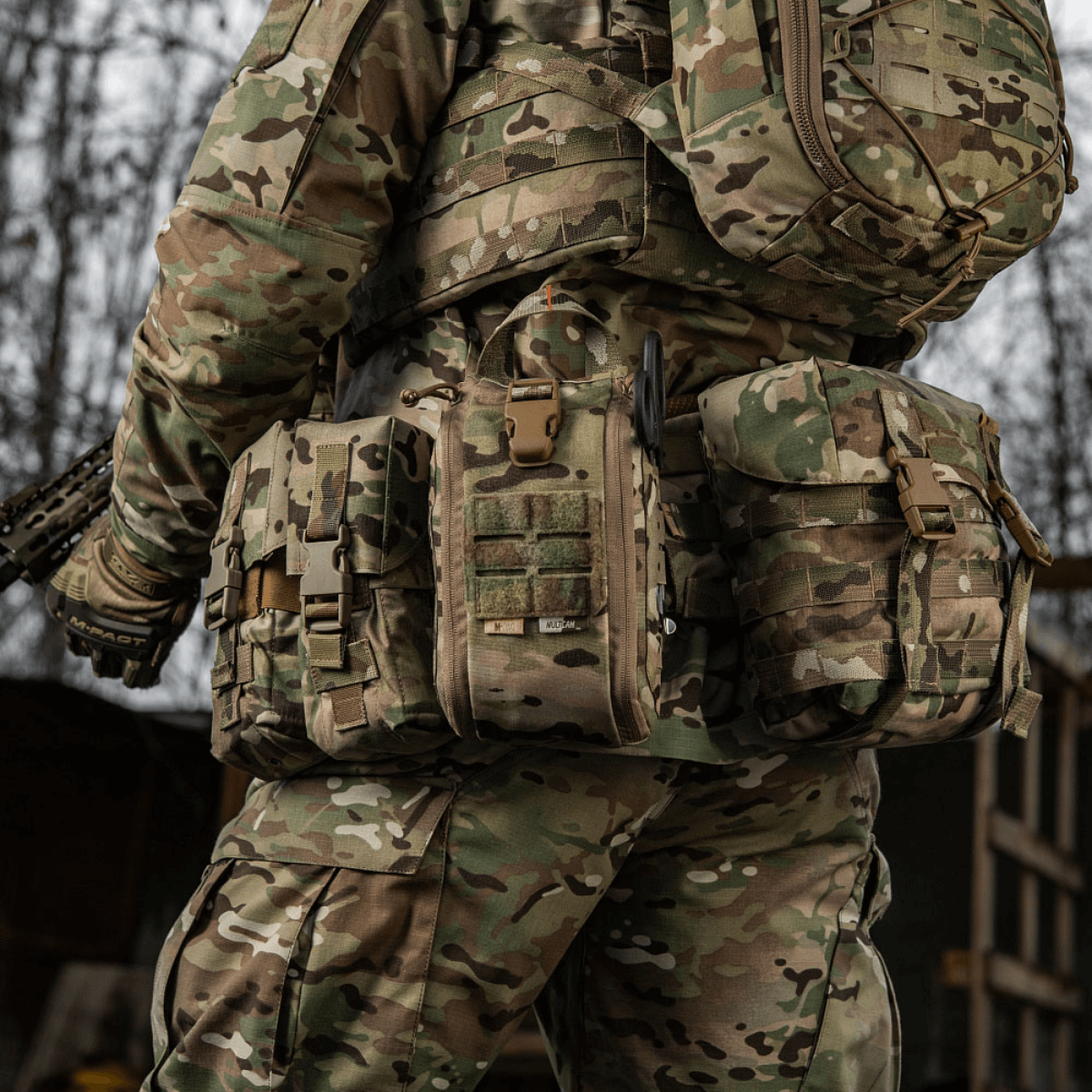 Soldat iført camouflageuniform med M-Tac Medical Pouch Elite Rip Off førstehjælpstaske for hurtig adgang til medicinsk udstyr.