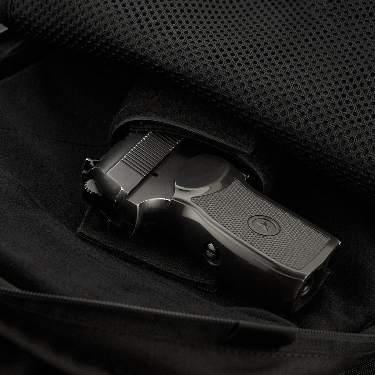 Indvendigt rum i M-Tac Magnet XL Bag Elite med universalholster, vist med pistol, fremhæver funktionalitet og sikkerhed i tasken.