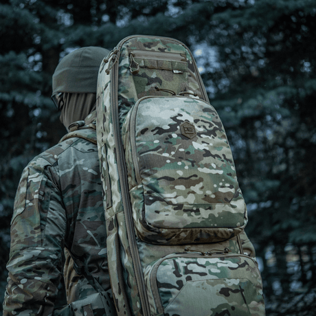 Hunter carrying camouflage M-Tac Gun Backpack Case 125 cm Gen.II Elite in a forest area