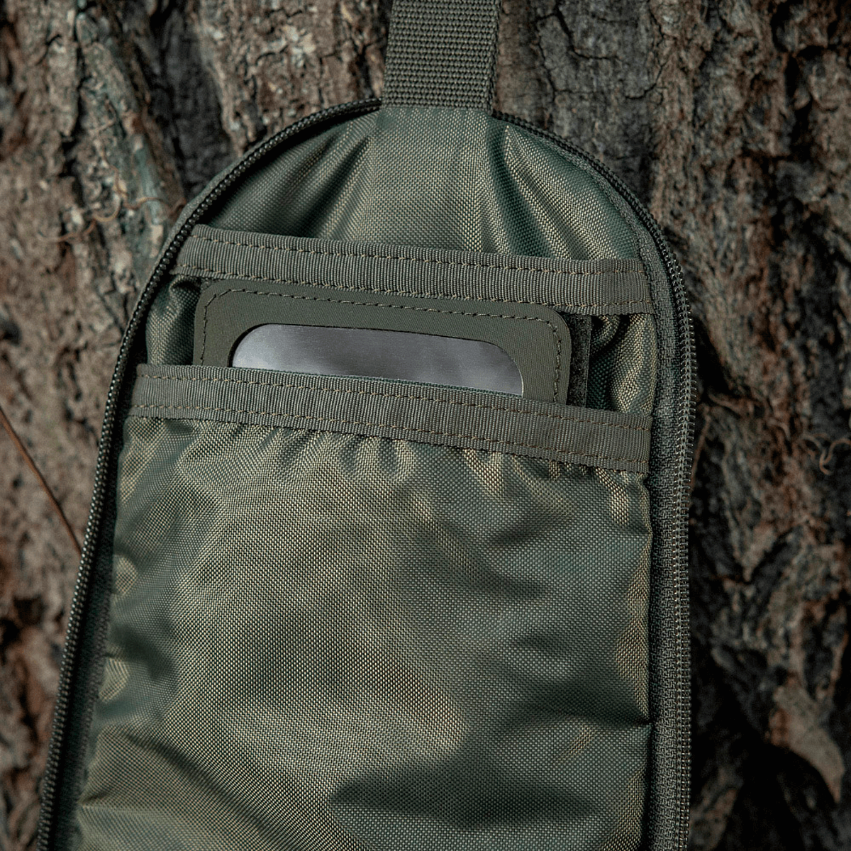 M-Tac Toilettaske Elite Gen.II hængende på et træ, viser indvendig opbevaringsplads til hygiejneartikler, ideel til rejser.