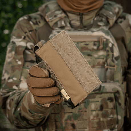 M-Tac Tourniquet Pouch Elastic VELCRO Gen.II in camouflaged surroundings, held by a person with tactical gear