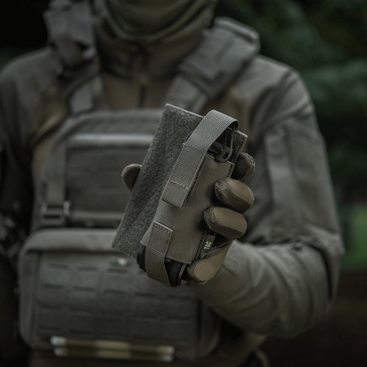 M-Tac Tourniquet Pouch Elastisk VELCRO Gen.II holdes af en taktisk udstyret person for hurtig adgang til tourniquet