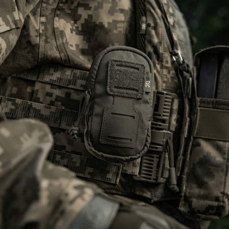 Soldier with M-Tac PC Utility Pouch Elite mounted on MOLLE system, versatile Cordura pouch for small items in tactical setting.