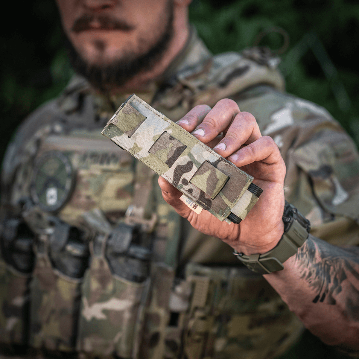 M-Tac Tourniquet Pouch Elastisk med MOLLE Gen.II i camo-design bliver holdt af person med taktisk udstyr, viser let adgang og opbevaring.