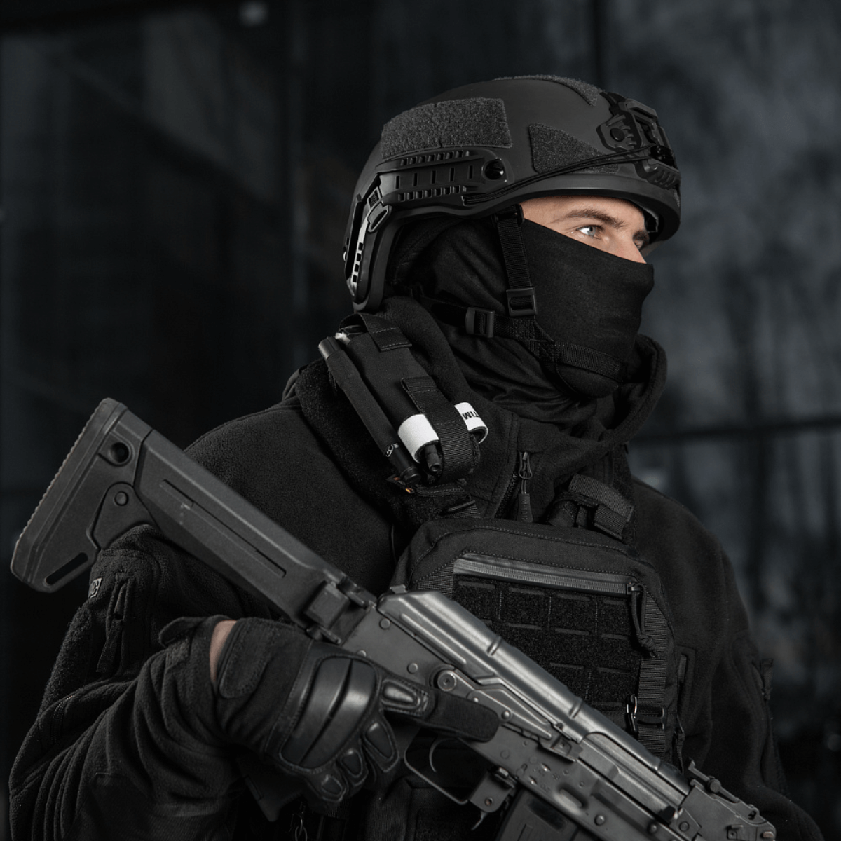 Taktisk person iført sort tøj og hjelm med våben og udstyr, klar til mission.