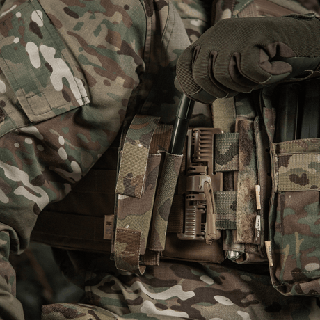 M-Tac Elastisk Tourniquet Pouch Molle Gen.III i brug, monteret på en militærvest i camouflagemønster med bred elastik til sikker fastgørelse.