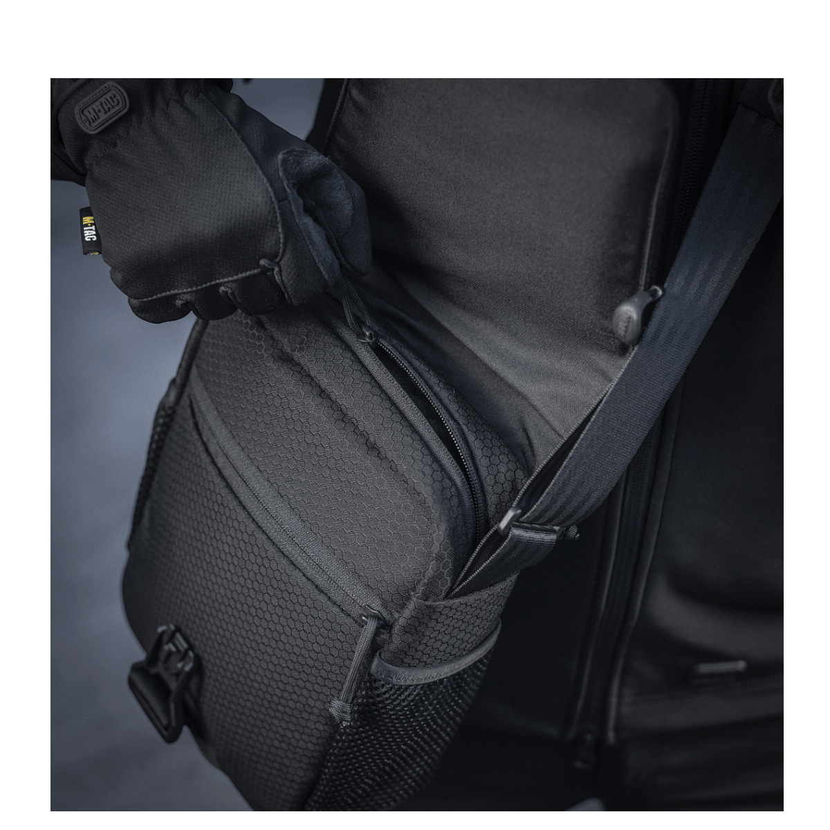Person åbner M-Tac Satellite Magnettaske Gen. II Elite Hex i slidstærkt Cordura materiale med YKK lynlåse og Woojin spænder.