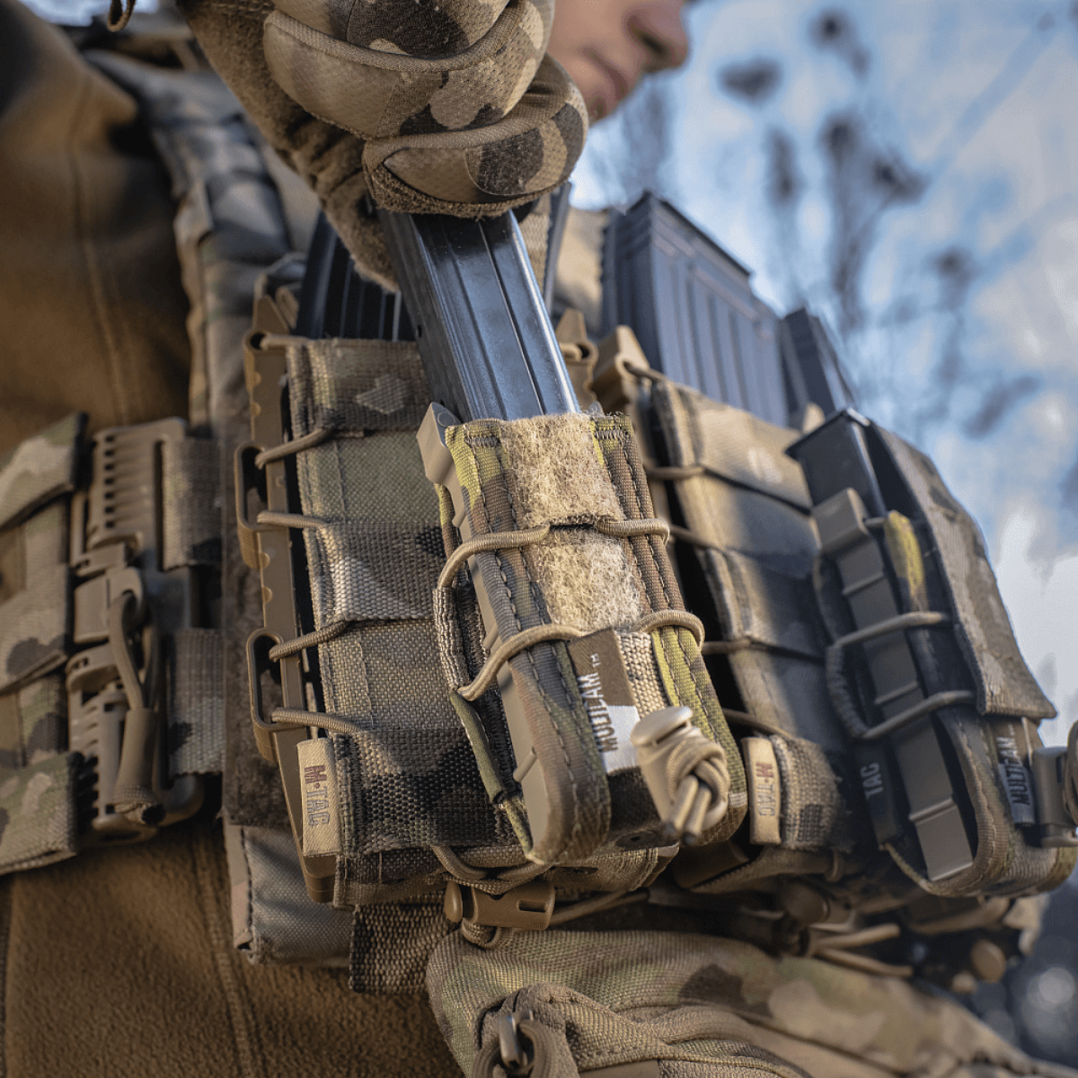 Taktisk udstyr med M-Tac Pistol Mag Pouch Gen.3 monteret på MOLLE-system, set i brug udendørs.
