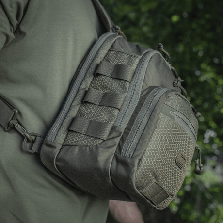 M‑Tac Cross Bag Elite Hex sling pack in Cordura 500, shown on shoulder in green surroundings, suitable for daily use and tactical gear. 5 liters.
