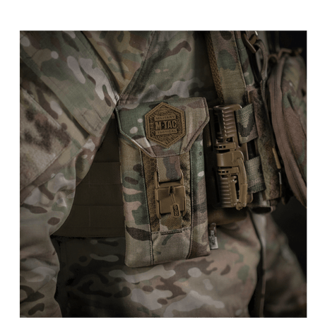 M-Tac Smartphone Lomme Elite Large Hex i CORDURA HEX materiale, vist monteret på taktisk udstyr med en camouflagebaggrund.