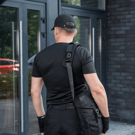 Man with bag wearing M‑Tac Shoulder Strap Pad 50 mm Elite at an entrance door.