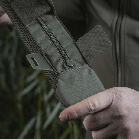 Person holding M‑Tac Shoulder Strap Pad 50 mm Elite in rugged Cordura material with zipper closure and 3D mesh ventilation.