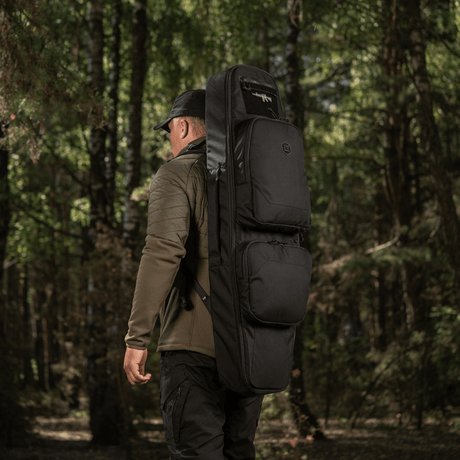 Man carrying M-Tac Gun Backpack Case 105 cm Elite Hex through the forest, ideal for AR-15 and AK carbine transport. Cordura 500D material.