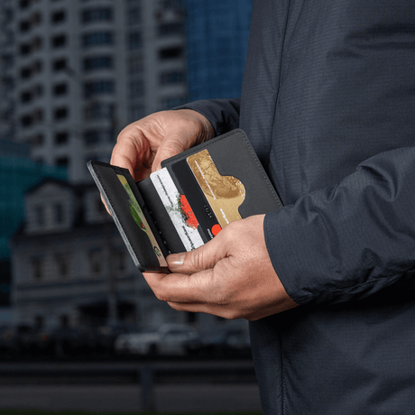 Man holds an M‑Tac Pung Slim Elite with cards and bills, stylish and compact wallet for secure storage.