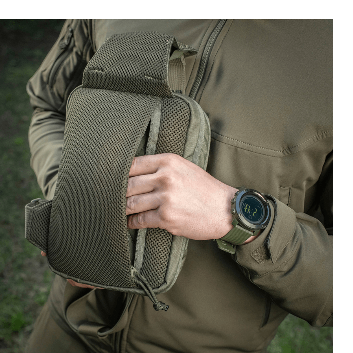 Person viser M-Tac Sling Pistoltaske Elite Hex i holdbart Cordura 1000D stof med justerbar skulderrem udendørs.