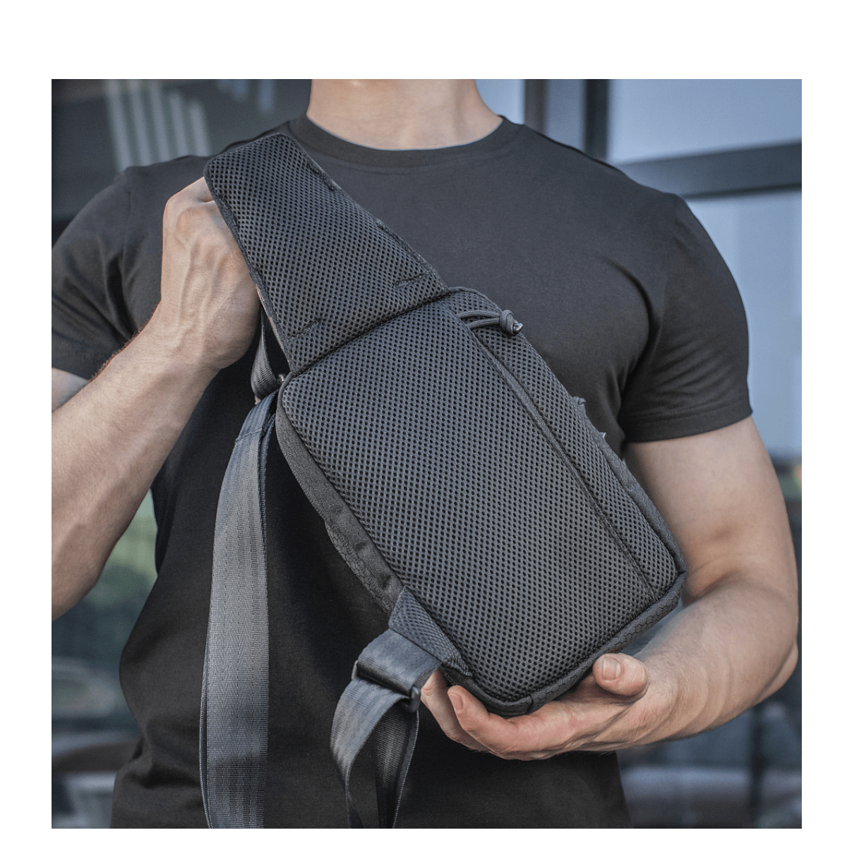 M-Tac Sling Pistoltaske Elite Hex båret af en person, sort, med komfortabel og justerbar skulderrem, lavet af slidstærkt Cordura materiale.