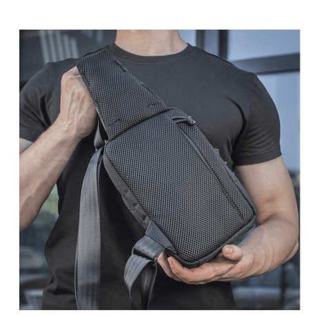Person carrying M-Tac Sling Pistol Bag Elite Hex, a comfortable, durable bag with adjustable shoulder strap and wear-resistant material.