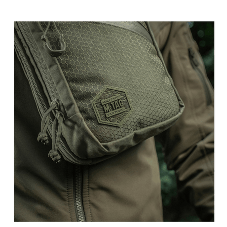 M-Tac Sling Pistol Bag Elite Hex on a person wearing a jacket, made from Cordura 1000D with an adjustable strap.