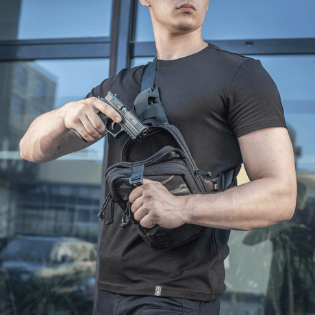Man with M-Tac Sling Pistol Bag Elite Hex demonstrating concealed weapon use. Comfortable and wear-resistant bag for discreet transport.