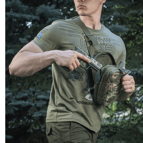 Man wearing M-Tac Sling Pistol Bag Elite Hex with a concealed pistol in the forest.