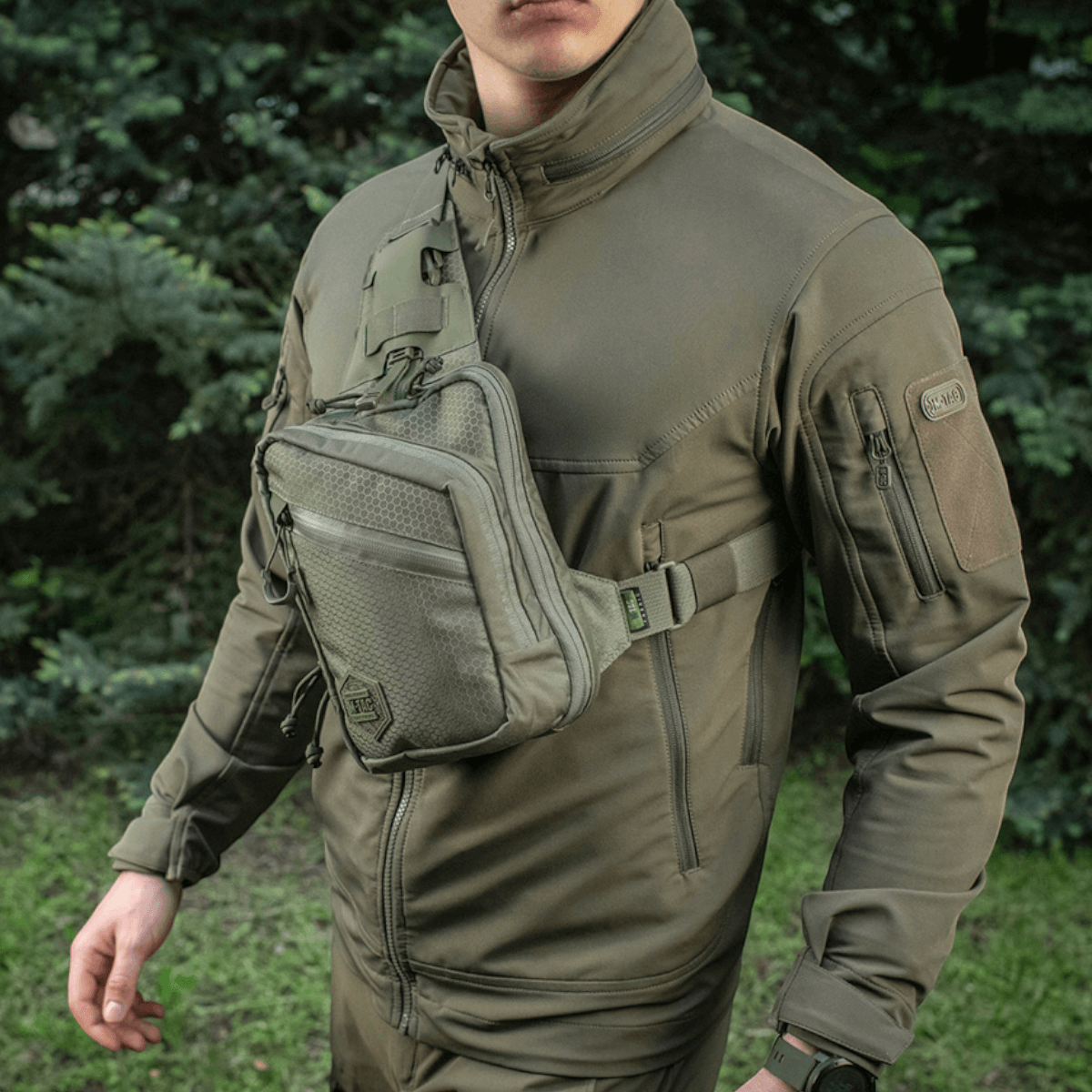 Mand bærer M-Tac Sling Pistoltaske Elite Hex i Cordura 1000D, med fire rum og justerbar skulderrem, perfekt til skjult våben transport.