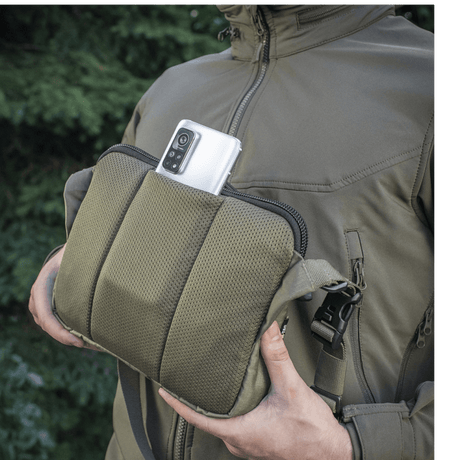 M-Tac Admin Bag Elite in Cordura fabric shown with a smartphone in the pocket, adjustable shoulder strap and solid construction, outdoor background.