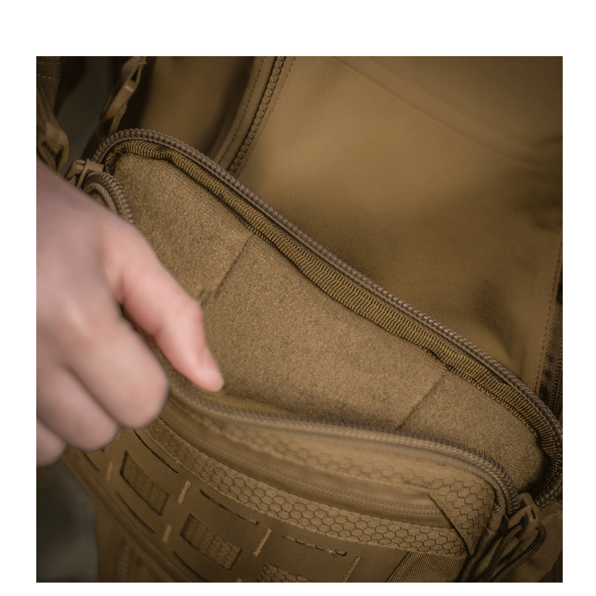 Person åbner lomme på M-Tac Admin Taske Elite lavet af slidstærkt Cordura materiale med YKK lynlåse.