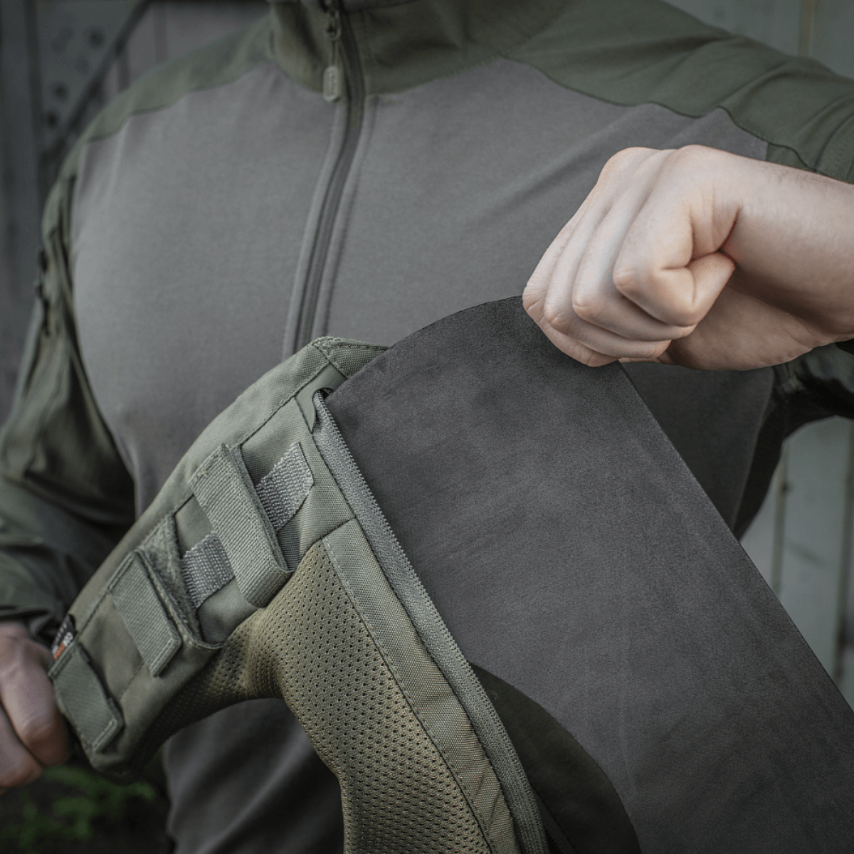 Person demonstrerer montering af M-Tac Skulderpude til Plate Carrier Cuirass QRS på jakke med Velcro fastgørelsessystem.