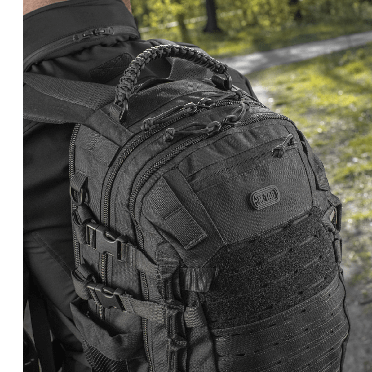 Mand iført M-Tac Mission Pack Elite rygsæk med ergonomisk design og MOLLE LASER CUT-system i skovmiljø