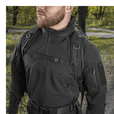 Man carrying M-Tac Mission Pack Elite backpack in a forest area, showing durable and stylish design in Cordura 1000D fabric.