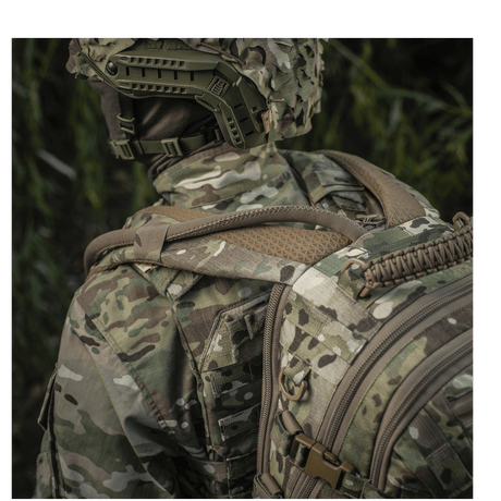 Person wearing camouflage uniform and M-Tac Mission Pack Elite with MOLLE LASER CUT in a forest environment for ergonomic functionality.