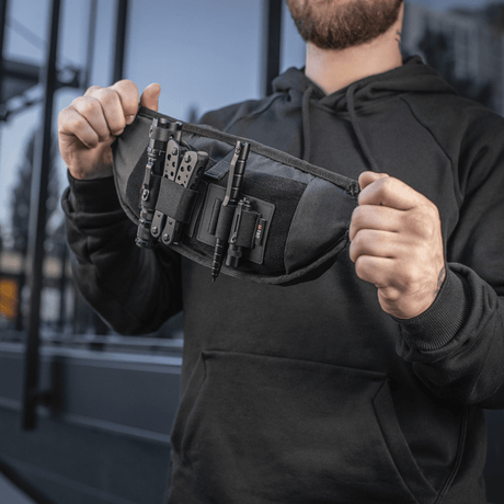 Man holding M‑Tac Elite Hex belt bag, compact and functional with Cordura fabric and YKK zippers, suited for tactical gear.