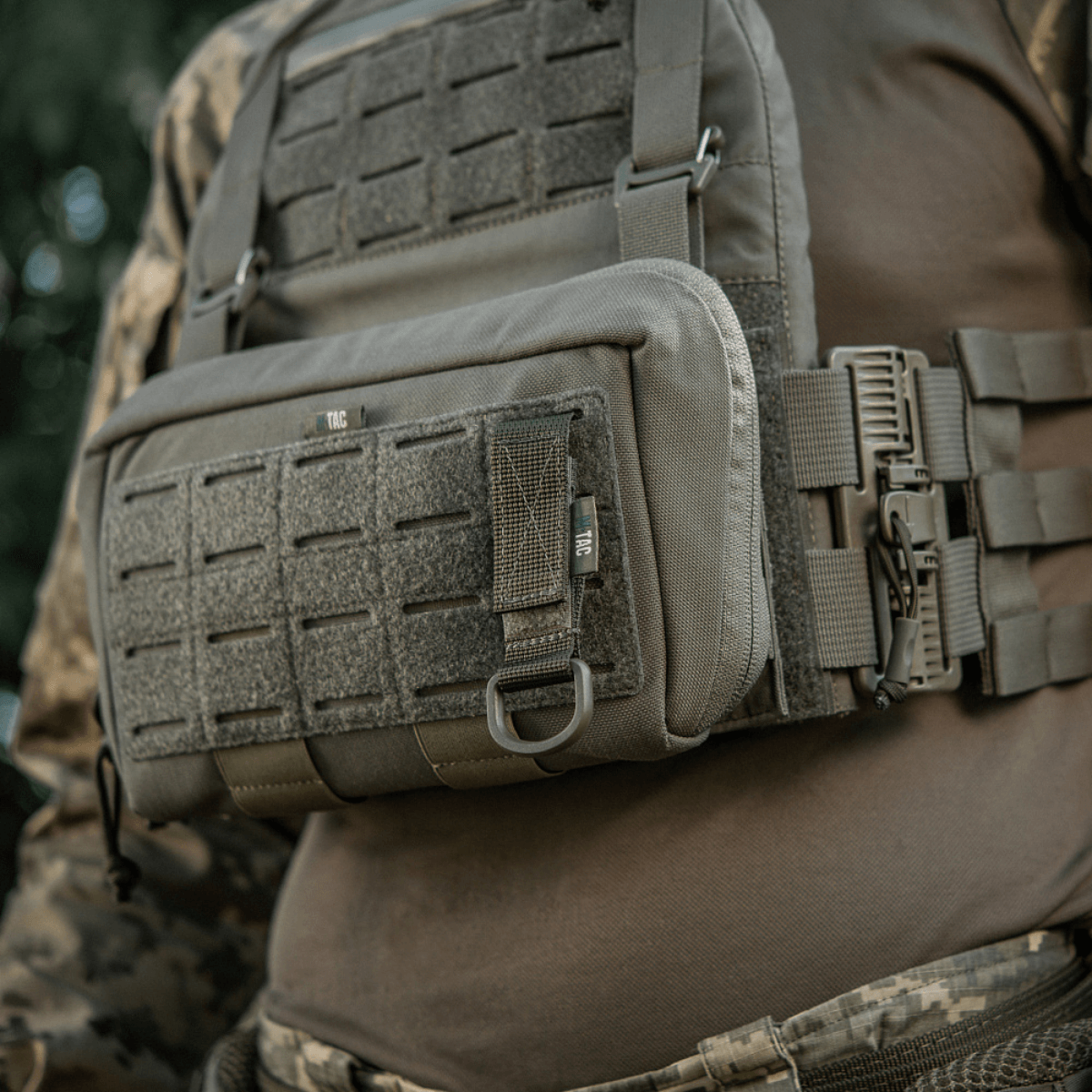 M-Tac Fastgørelse med D-ring monteret på taktikvest med MOLLE-system for sikker ophængning af udstyr via Velcro-lukning.