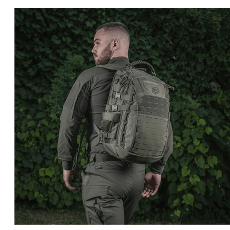 Person with an M-Tac Mission Backpack Elite Hex against a backdrop of green vegetation.
