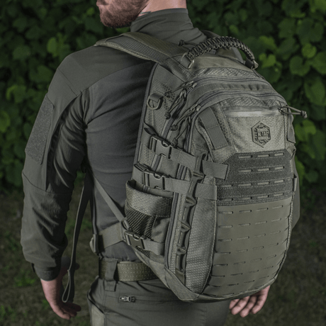M-Tac Mission Backpack Elite Hex on the back of a person in tactical clothing, with Cordura material and MOLLE system, seen from behind in nature.