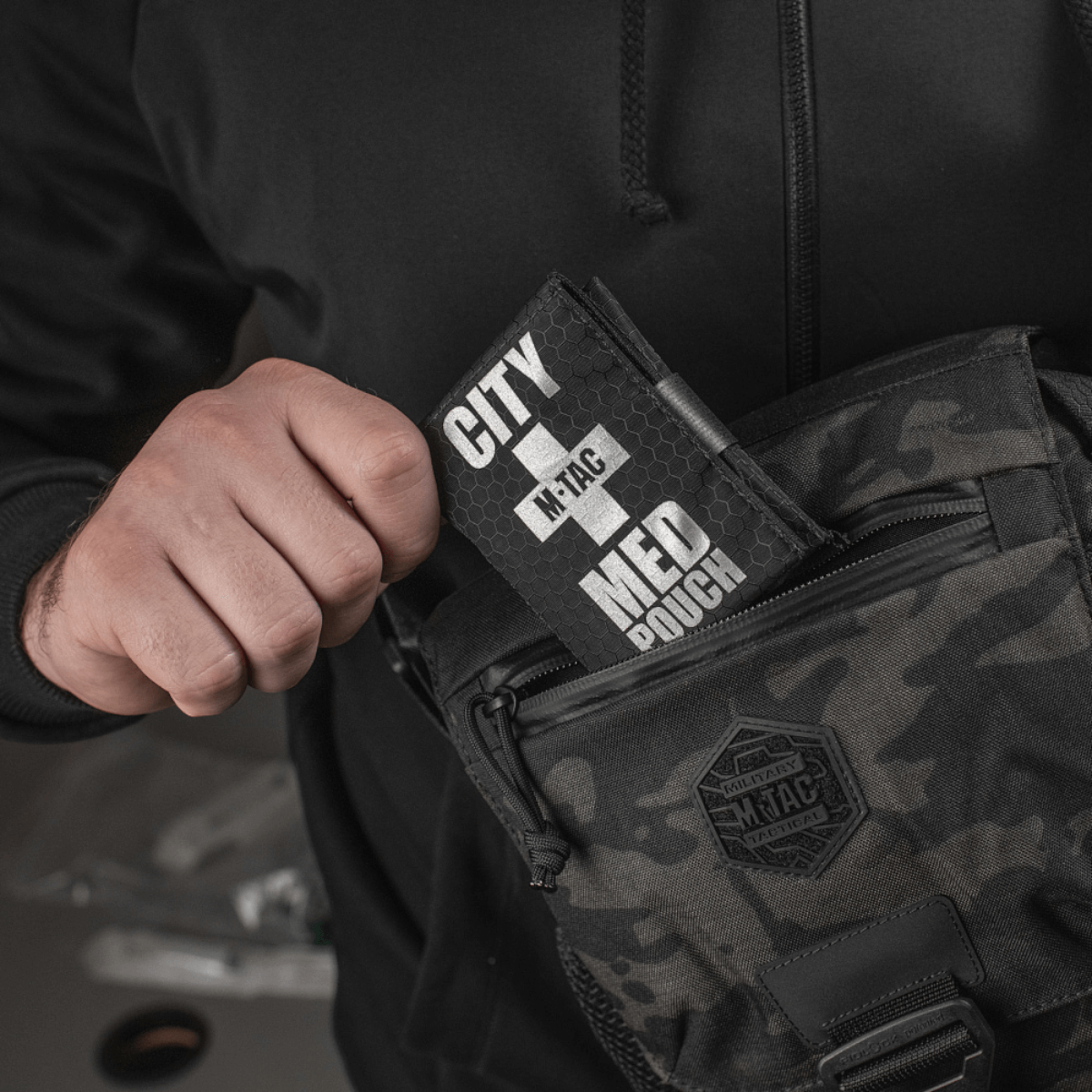 Person holder M-Tac City Med Pouch Hex i en camouflagemønstret taske, fremstillet af slidstærkt Hex Polyester materiale.