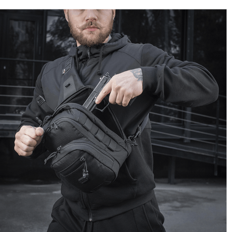 Man wearing M-Tac Cross Bag Slim Elite Hex in black with Cordura materials, YKK zippers and Woojin buckles, outdoor setting.