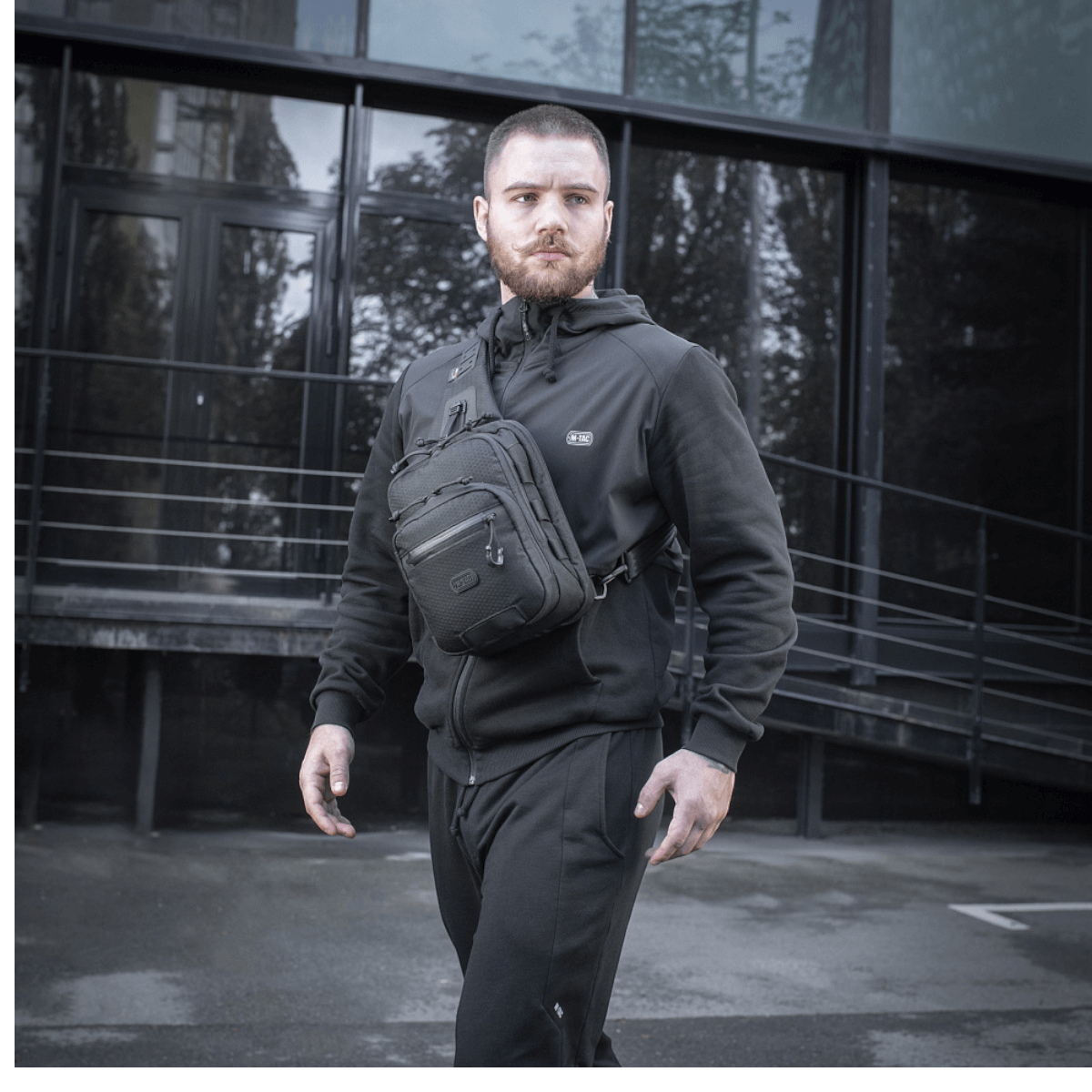 Mand bærer M-Tac Cross Taske Slim Elite Hex udendørs i urban omgivelser.