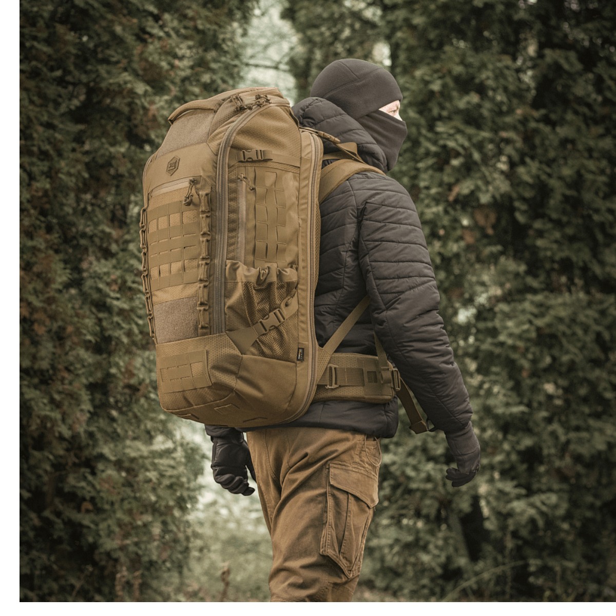 En person iført M-Tac Rygsæk Large Elite Hex Gen. IV i naturen, designet til holdbarhed og funktionalitet.