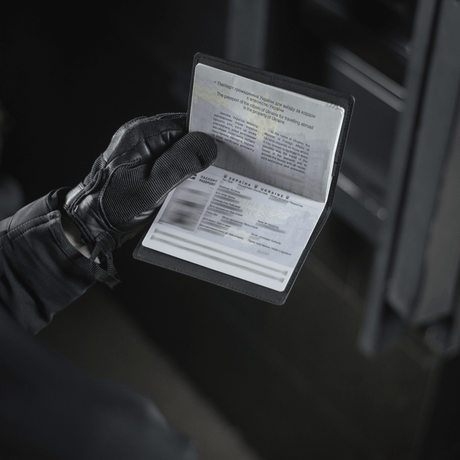 Person wearing gloves holding an M‑Tac passport cover protecting a passport, with space for plastic cards and stylish logo. Dimensions: 13.5 x 10 cm.
