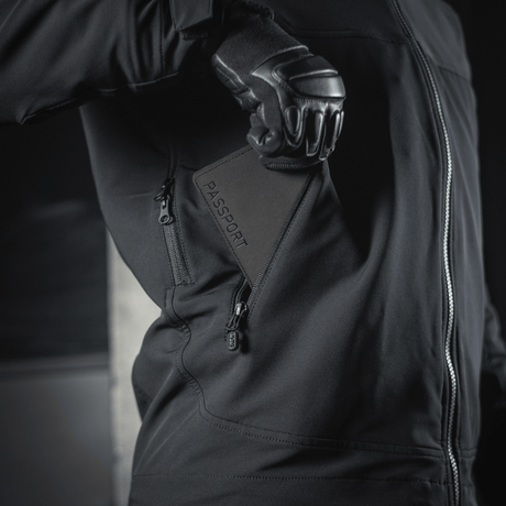 Person in a black jacket holding an M‑Tac passport cover with 'Passport' print, practical for travel.