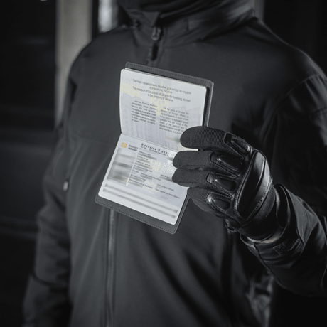Person holding an M‑Tac passport cover and passport, protects against wear and damage, modern polymer, stylish design, ideal for travel.