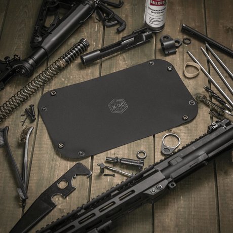 M‑Tac Field Maintenance Tray 18x30 cm used for weapon maintenance, surrounded by tools and parts, polymer composite material.