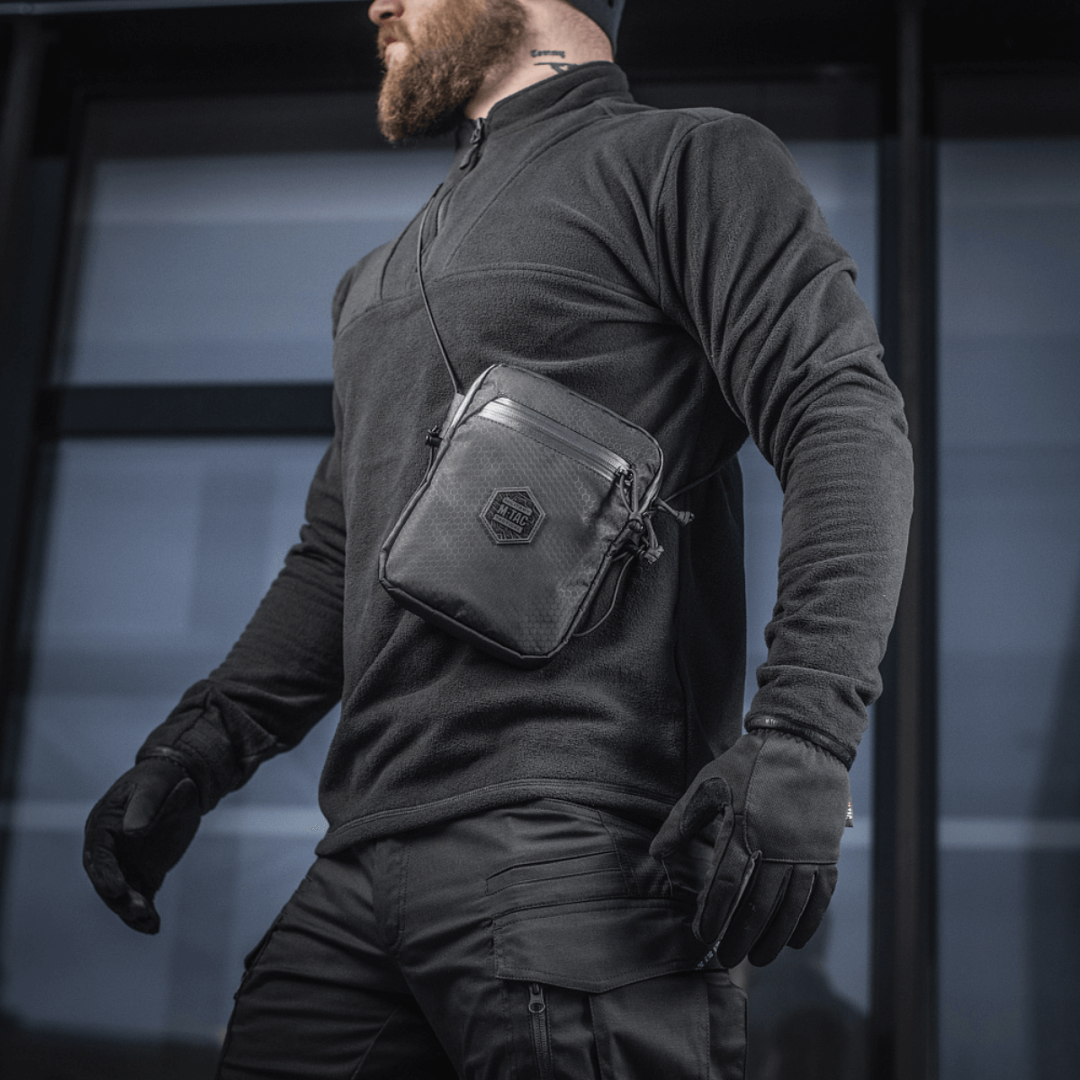 Mand bærer M‑Tac Pocket Bag Elite HEX i sort, robust taske til EDC-udstyr og daglig brug, med høj kvalitet YKK lynlåse.