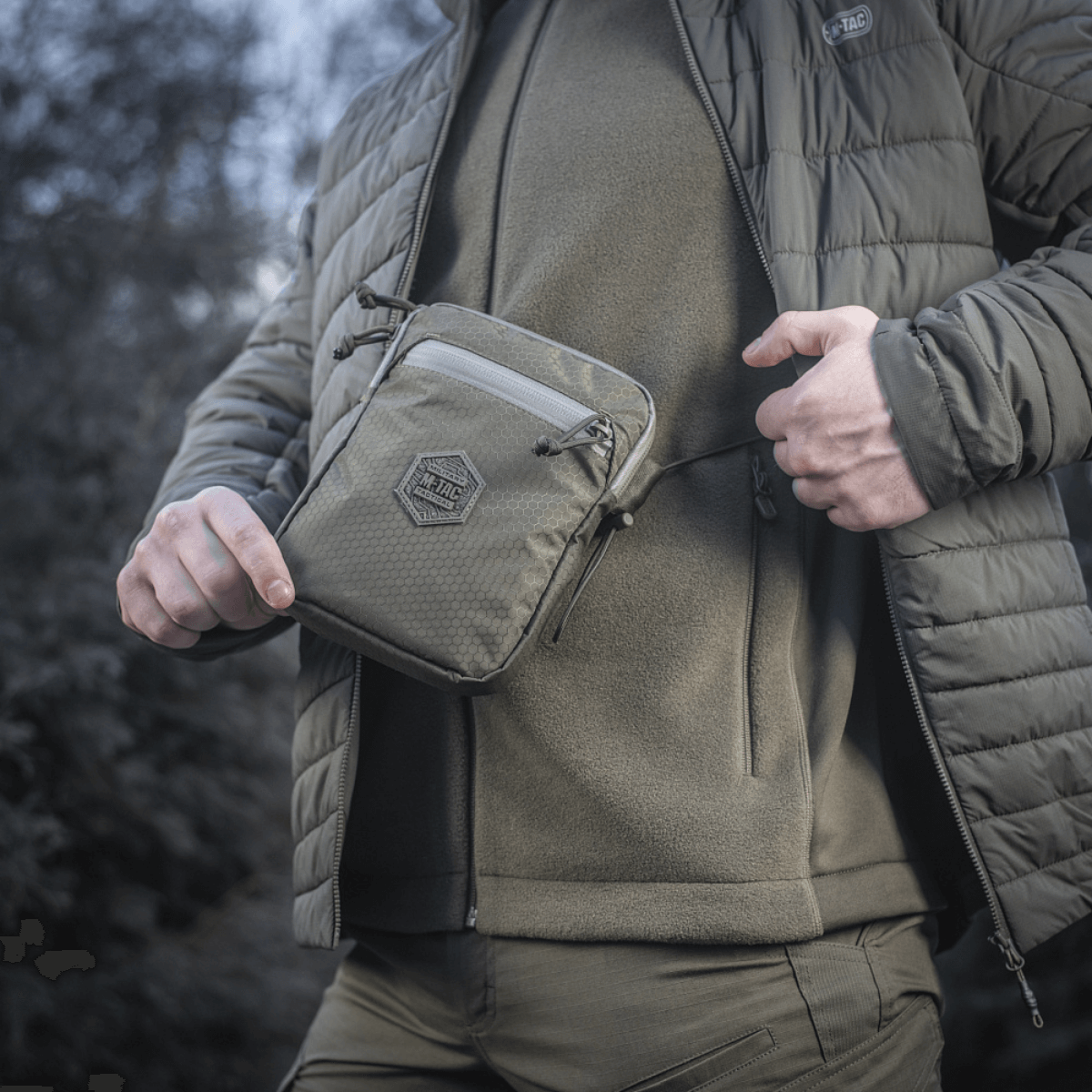 Mand bærer M‑Tac Pocket Bag Elite HEX udendørs. Kompakt og holdbar taske til EDC-udstyr med YKK lynlås. Ideel til daglig brug.