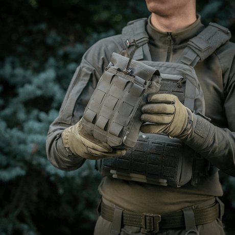 M‑Tac Medic Pouch Vertical Large Elite i brug, holdt af person i militær påklædning med udsigt over taktisk baggrund.