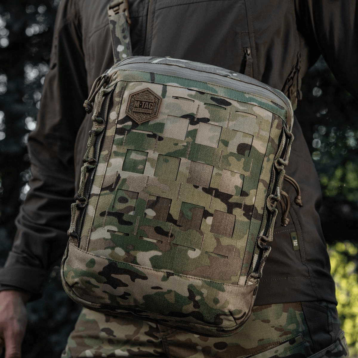 M-Tac Tablet Bag Laser Cut Hex i camouflage med MOLLE-system, båret af en person i naturen, ideel til EDC og skjult våbenopbevaring.